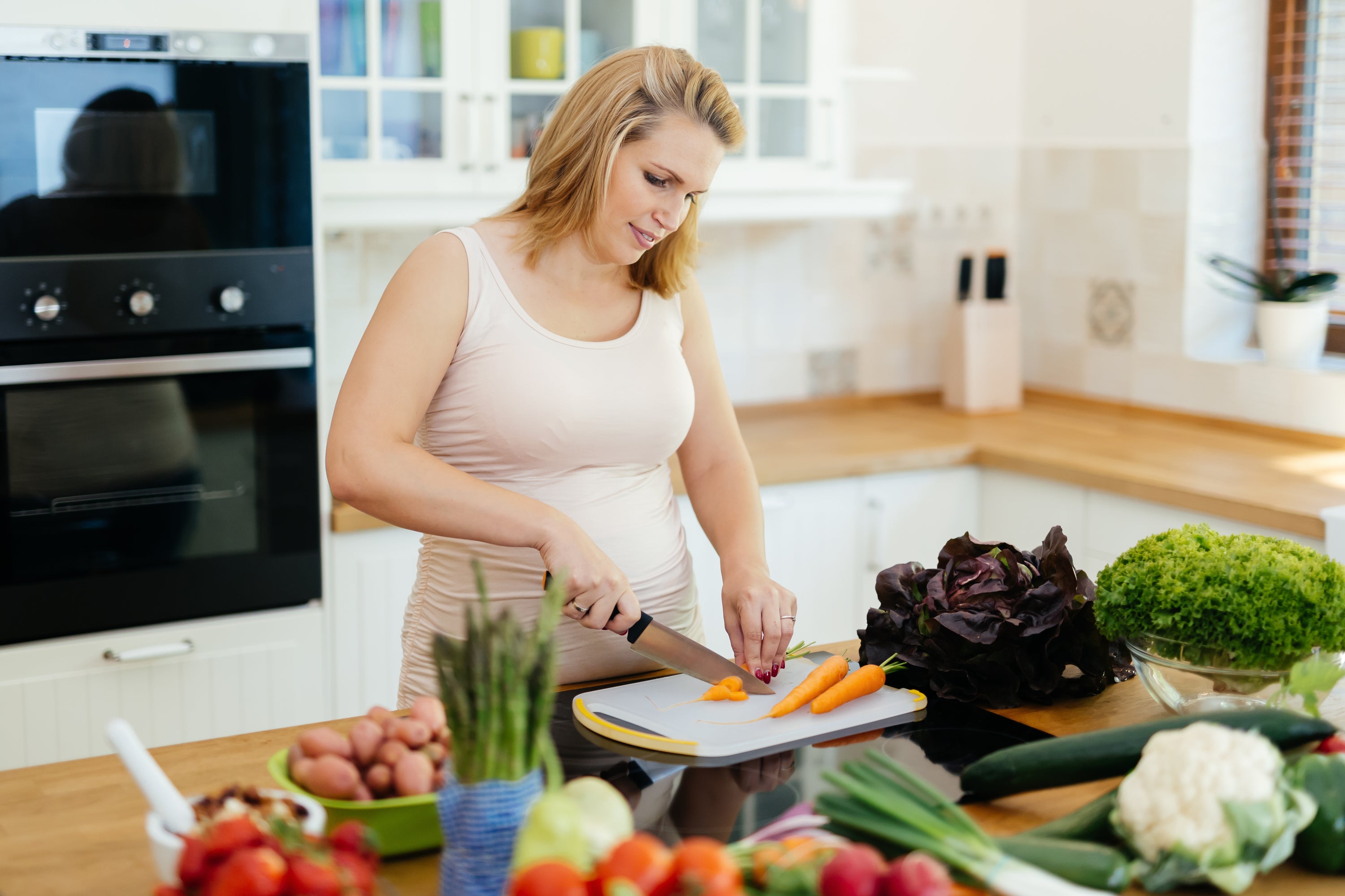 Women cutting vegetables to control her Ghreling levels better known as hunger hormone.