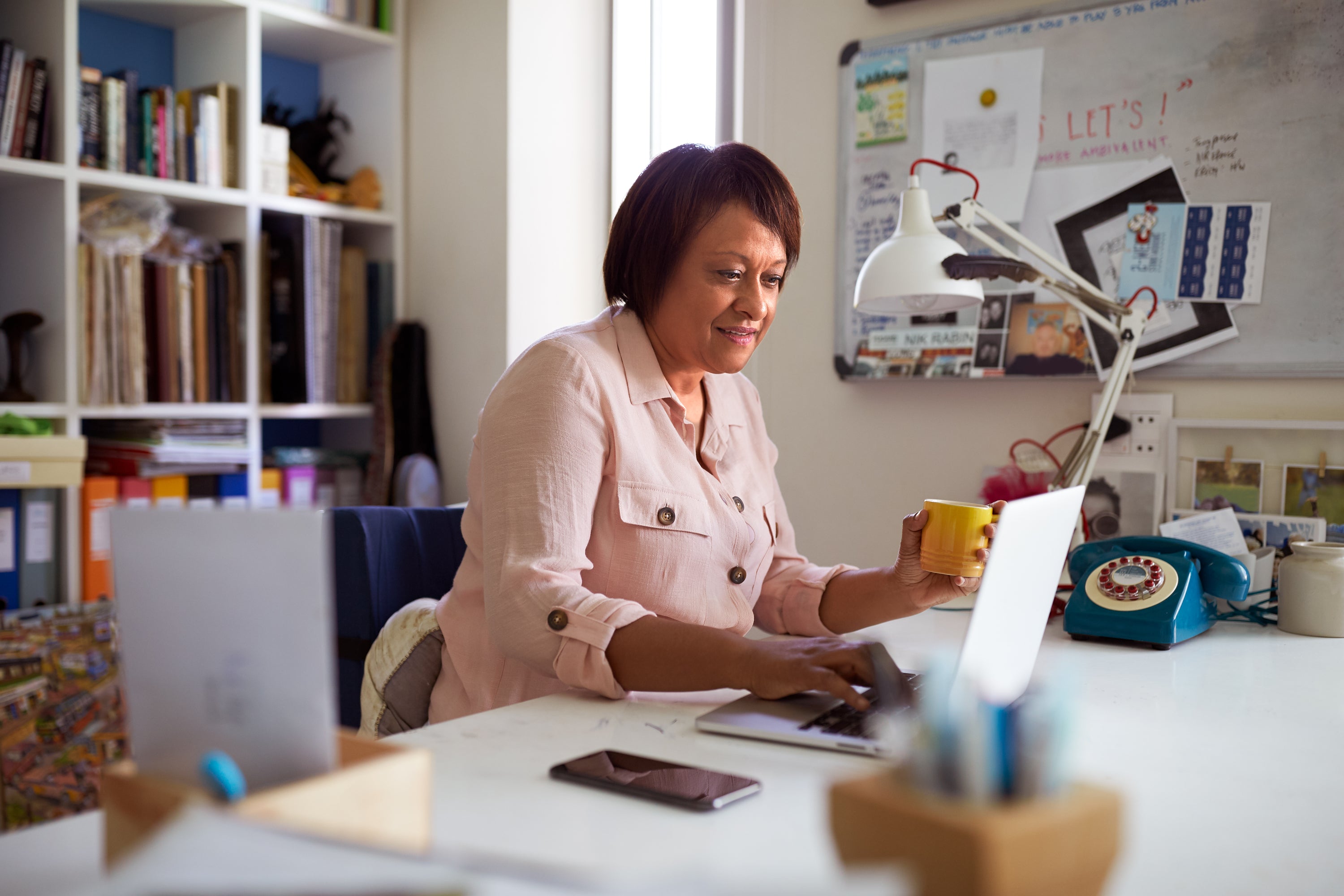 Person looking at the computer holding a cup in her had